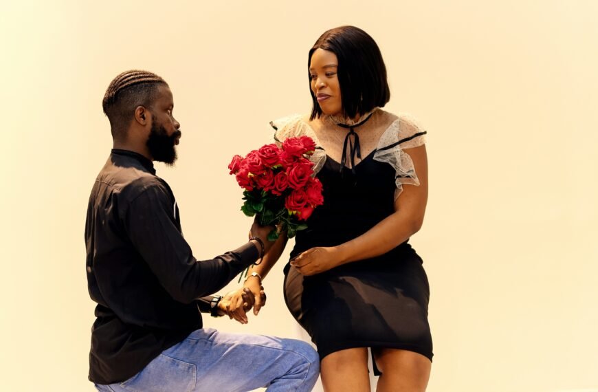 A man kneeling down next to a woman holding a bouquet of flowers